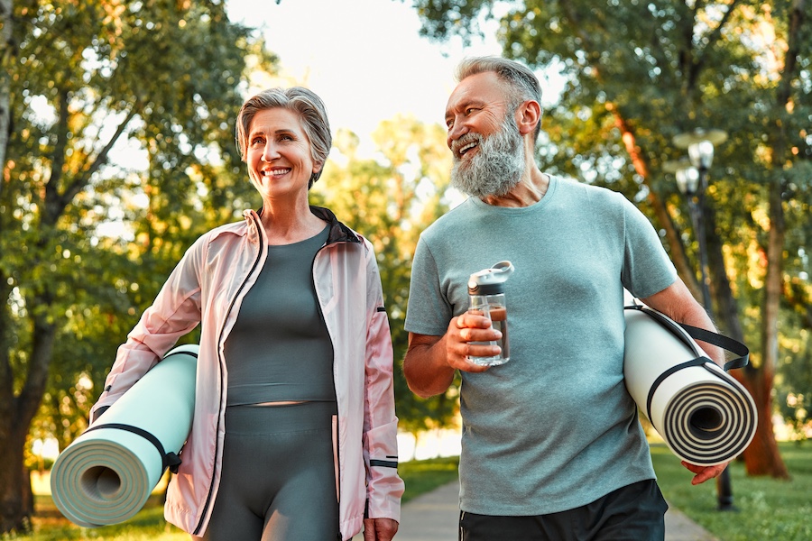 Older couple walking with yoga mats